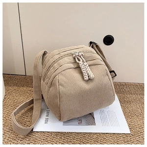 Detail of beige corduroy shell bag with dual zipper closure and woven rope pullers