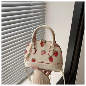 Close-up of strawberry print handbag featuring gold zippers and textured faux leather