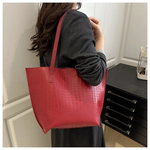 Detailed close-up of a large red crocodile texture tote bag on a model's shoulder