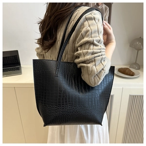 Detail of high-quality black crocodile embossed tote bag with slim shoulder straps