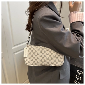 Close-up of cream monogram shoulder bag with gray M pattern and leather strap on model