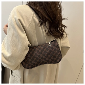 Detail view of brown monogram crescent bag with silver zipper on beige trench coat