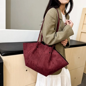 Large burgundy matte leather tote bag with knotted straps worn with green blazer