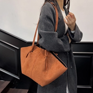Minimalist orange-brown suede tote bag worn with grey coat for autumn commute