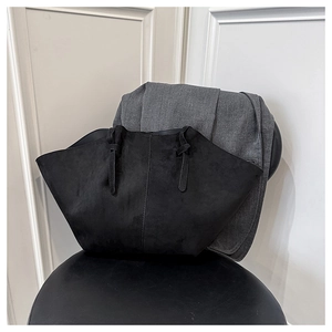 Detailed view of matte black suede wing tote bag with elegant twisted handle design