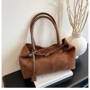 Detail of brown faux suede tote bag with decorative metal buckle and soft texture