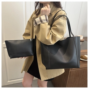 Detail of the black leather tote bag and zipper pouch set worn with a trench coat