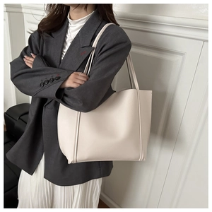 Model wearing a minimalist cream-colored large tote bag made of high-quality leather