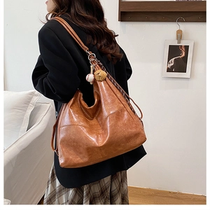 Caramel retro hobo bag with diamond stitching detail and baseball charm on a model