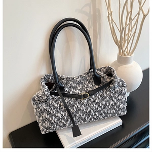 Detail of black and white tweed tote bag with leather straps and gold hardware
