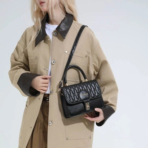 Chic black quilted crossbody bag with gold hardware shown on a model in a khaki coat