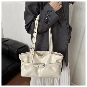On-shoulder view of the cream leather tote bag with stylish buckle strap details