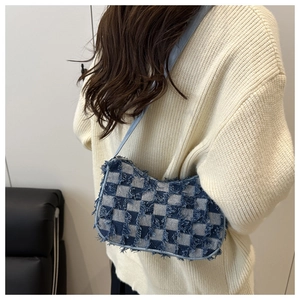 Detail view of denim checkerboard shoulder bag featuring stylish frayed edge and leather strap