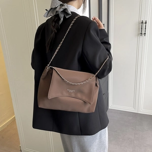 Sac fourre-tout marron minimaliste avec chaîne en métal porté à l'épaule par le mannequin