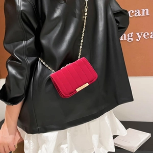 Red velvet quilted crossbody bag with gold chain strap worn with black leather jacket