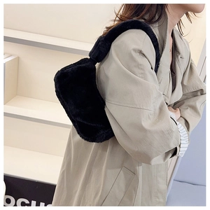 Detail view of black faux fur crescent shoulder bag styled with a beige trench coat