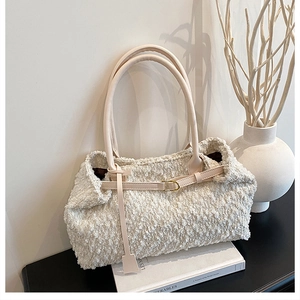 Detail of creamy white fuzzy tote bag with leather strap and gold metal buckle
