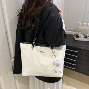 Large white tote bag with black leather straps and plush charm for daily commuting