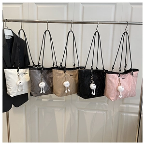 Detail of nylon tote bags in various colors with cute plush monster charms and thin straps