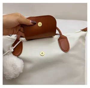 Détail du sac cabas blanc avec rabat en cuir marron et fermoir magnétique en métal doré