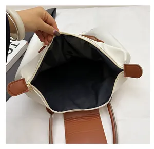 Détail de l'intérieur d'un grand sac cabas crème avec poignées en cuir marron et fermeture