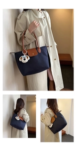 Détail du sac fourre-tout en toile bleu marine avec poignées en cuir et charm peluche