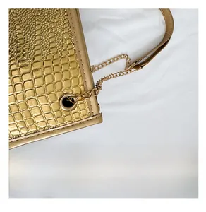 Détail du sac à main doré motif crocodile avec bandoulière en chaîne métallique