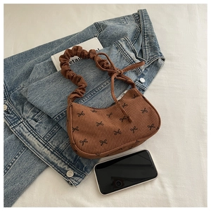 Detailed texture of brown corduroy bag with black bow print and ruched shoulder strap