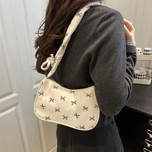 White corduroy shoulder bag with black bow patterns and knotted strap detail