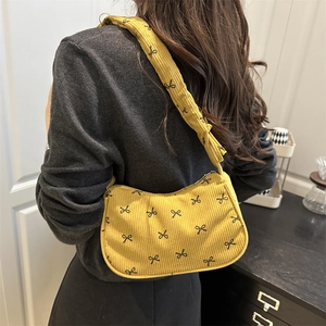 Yellow corduroy shoulder bag with black bow print and textured quilted pattern