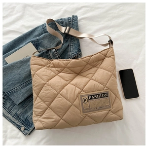 Détail du sac matelassé kaki avec étiquette mode sur fond de tissu blanc élégant