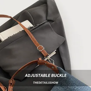 Close-up of adjustable brown leather strap with silver buckle on blue denim bag