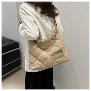 Detail of beige quilted tote bag with diamond pattern and fashion brand label