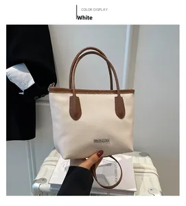 Detailed close-up of white pebble leather tote bag with brown trim and fashion logo