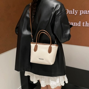 Chic beige lychee grain bucket bag with brown handles and a slender crossbody strap
