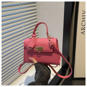Close-up of pink lychee grain leather bag with a unique gold heart-shaped gear clasp
