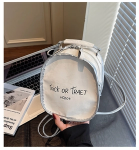 Close-up of white and silver backpack with letter print in a modern office setting