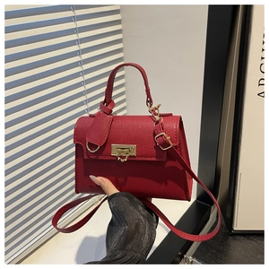 Detailed view of dark red lychee leather handbag with elegant gold metal lock and hardware