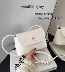 Détail du mini sac en cuir PU blanc avec boucle nœud argentée et bandoulière tissée