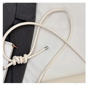 Détail de la bandoulière en cuir blanc crème avec nœud et embouts métalliques argentés