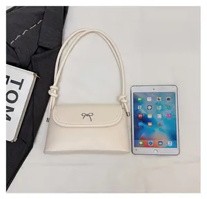Sac bandoulière beige comparaison de taille avec iPad avec nœud argenté et détails noués