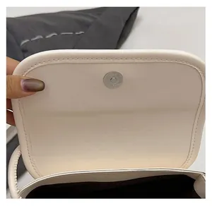 Détail du fermoir magnétique sur le sac à main en cuir beige avec coutures précises