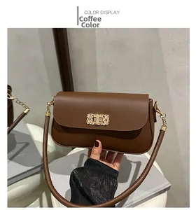 Close-up of a brown leather crossbody bag with a distinctive gold woven texture buckle