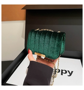 Macro detail of dark green velvet bag with vertical quilting and gold metal chain