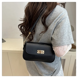 Détail d'un sac bandoulière noir avec fermoir tournant doré et bandoulière en chaîne