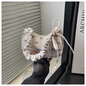 Détail de la texture velours côtelé et imprimé nœud noir sur sac bandoulière crème
