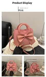Close-up of pink handbag featuring a large 3D bow, gold hardware, and top handle