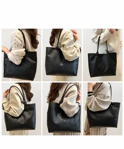 Close-up of black woven leather tote bag featuring detailed Intrecciato craftsmanship