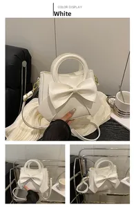 Close-up of a white fashion handbag with a large bow detail and round hard handle