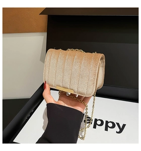 Detail of champagne gold velvet crossbody bag with vertical quilting and chain strap